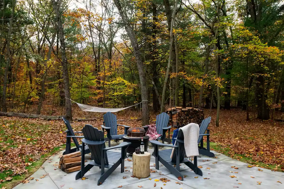 Adirondack chairs around a fire pit with trails running into the trees